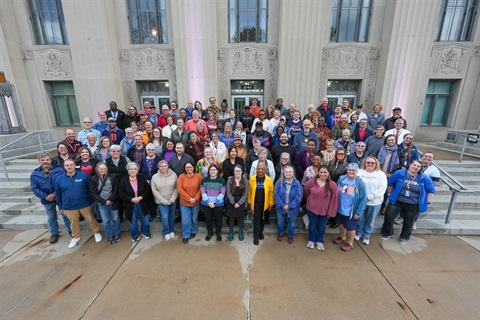 A group of election works stand on the steps of city hall.